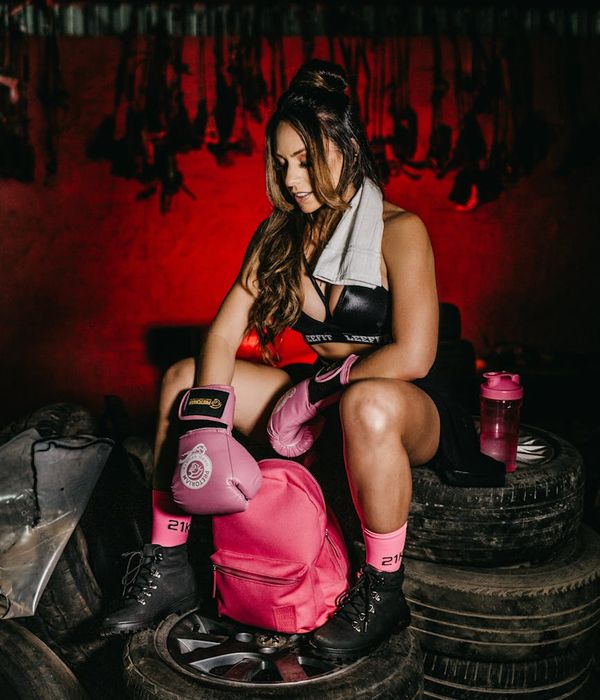 Woman in a calm, energetic pose against a dark background with pink accents.